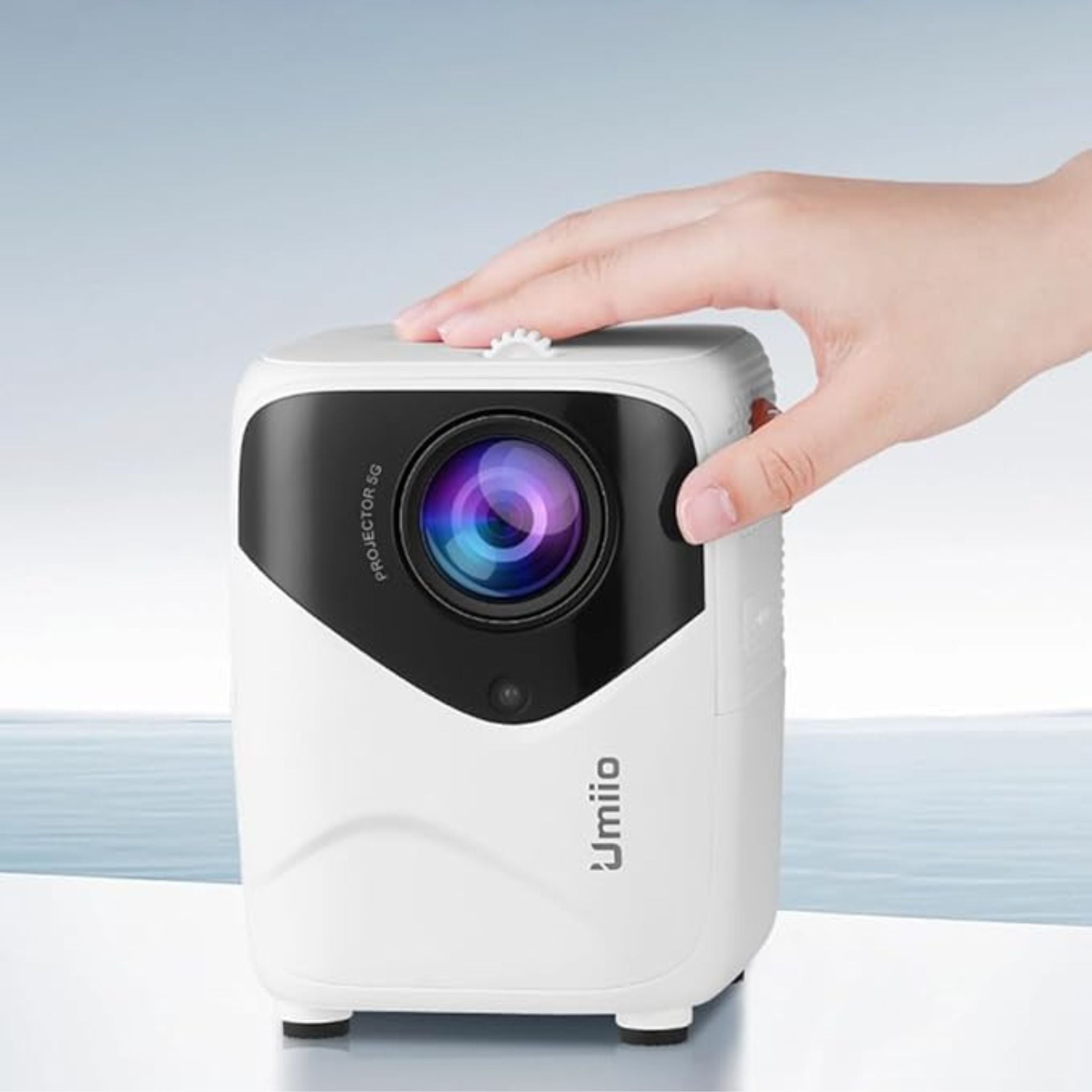 White projector with black accents held by a hand against a light blue background