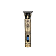 A gold-colored hair trimmer with an LCD display and a skull symbol on the metal body, resembling a pirate ship design.